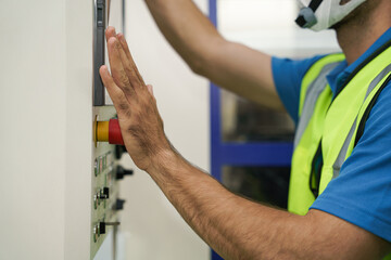 Obraz premium closeup of hand pressing red button on cnc machine control panel at factory