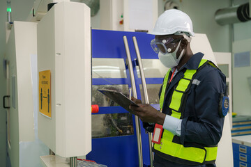 factory foreman with face mask operating with CNC machine control panel