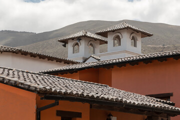 Fototapeta na wymiar approach to the infrastructure of an old house with a tile roof, in the background a mountain and sky with clouds