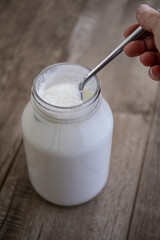 Yogurt in a Glass with a Hand and a Spoon.