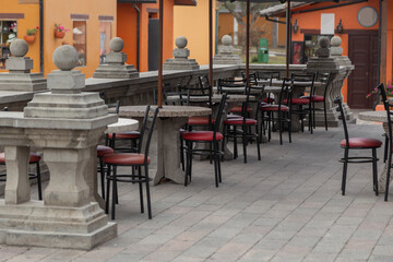 Fototapeta na wymiar restaurant with tables and chairs with red metal seat on a stone terrace with classic design handrail, outdoor decoration