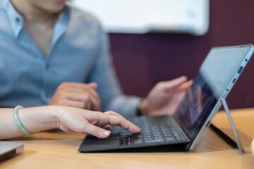 business man and woman working together on a laptop in a modern office environment. Close up of hands and screen