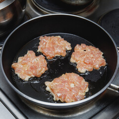 Raw chicken cutlets frying on pan, closeup