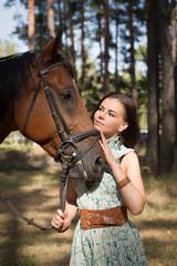 Obraz premium Young beautiful woman hugs her horse in the forest 