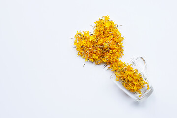 A glass cup with marigold flower petals on white background. Flower herbal tea concept.
