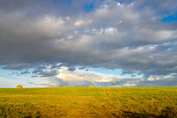 Rural landscape with clouds and harvested hay field