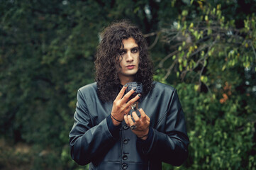 Stylish man with dark curly hair in a leather coat. Gothic style.