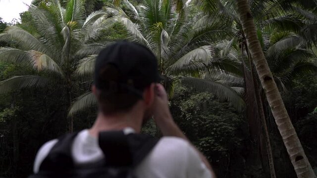 Man taking pictures of palm trees in jungle in south east Asia