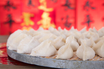 Wrapped white flour dumplings on a tray in front of a red background