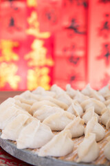 Wrapped white flour dumplings on a tray in front of a red background