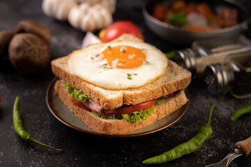 Breakfast sandwich made with bread, fried egg, ham, and lettuce.