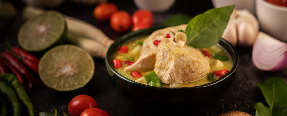 Fototapeta na wymiar Green curry made with chicken, chili, and basil, with tomato, lime, kaffir lime leaves and garlic.