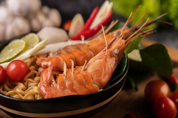 Tom Yum Kung in a bowl with tomato, chili, lemongrass, garlic, lemon, and kaffir lime leaves