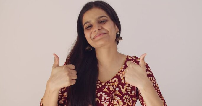Asian female with black hair hand gestures of best of luck with thumbs raised in shock and pleasantly surprised at the result wins someone calls her draws attention disbelief good news taken aback 
