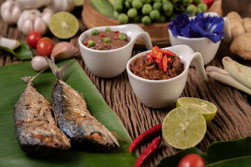 Shrimp paste, mackerel, fried on banana leaves, chili, tomato, garlic and lemon on wooden floor.