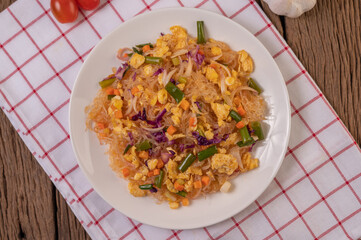 Stir fried glass noodles with eggs and put on a plate on a red white cloth.