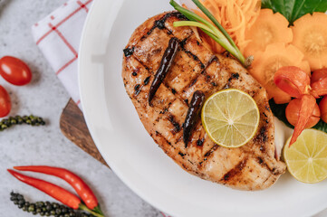 Chicken Steak with Lemon, Tomato, Chili, and Carrot on White Plate.