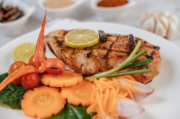 Chicken Steak with Lemon, Tomato, Chili, and Carrot on White Plate.