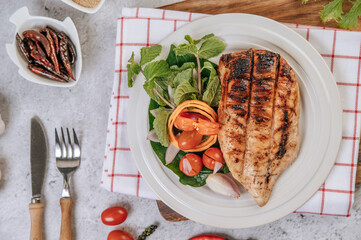 Chicken Steak with Lemon, Tomato, Chili, and Carrot on White Plate.