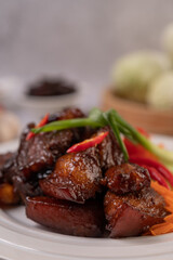 Sweet pork in a white plate with peppers, green onions, carrots, and tomatoes