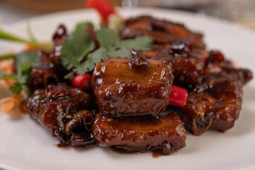 Sweet pork in a white plate with chili, spring onions, carrots, and coriander.