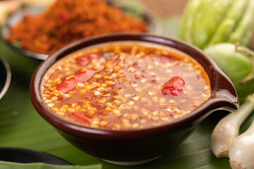 Chili sauce and ingredients placed on banana leaves.
