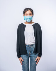 A woman is sick standing wearing a mask.