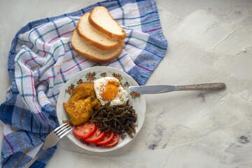 Healthy simple breakfast with poached egg, chicken steak, seaweed salad and tomato. Servings on a concrete background with a sealed napkin