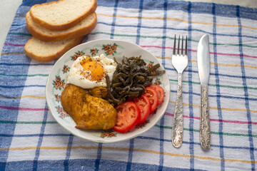 Healthy simple breakfast with poached egg, chicken steak, seaweed salad and tomato. Servings on a concrete background with a sealed napkin