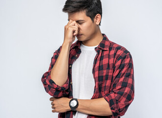 A man with a migraine headache holding her hand in her nose
