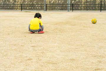 Toddler crouching in the sandbox.