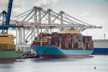 Fototapeta premium Big blue container ship alongside seaport dock.