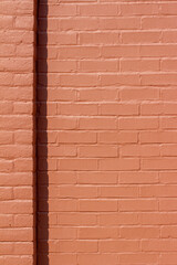 Red painted brick wall texture background with a slight corner shadow in full sunlight, with copy space