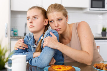 Woman asking for forgiveness from her teenage daughter in home interior