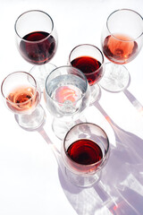 Glasses with red, white and rose wine on a white background.