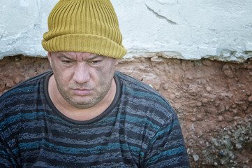 Portrait of a homeless man with a knitted hat and a dirty face. Looking off to the side.
