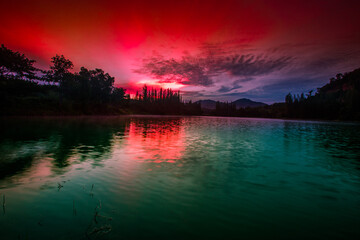 Blurred nature background view of naturally occurring trees and reflection on the water surface,...