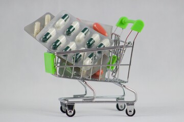 Green shopping cart with medicaments on an isolated white background. Empty green shopping cart on isolated white background. Go shopping.