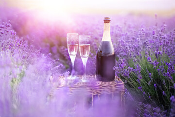 A bottle of champagne and glasses in a sunset lavender field.