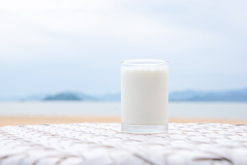 A glass of milk on white table next to the beach