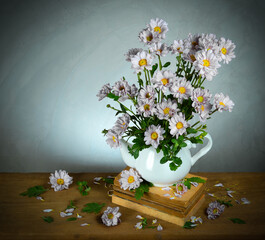 Blooming flowers in a vase, placed on an old book, on a vintage wooden table, a rough-polished cement wall, a beautiful and classic still life style.