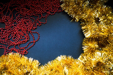Christmas golden tinsel and red garland on dark blue background. Happy New Year Banner, Merry Christmas. Xmas posters, greeting cards, headers, website, sale banner. Winter time. Frame. Top view.