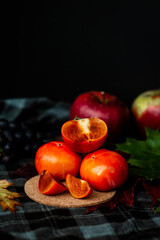 slices of ripe orange persimmon fruit, autumn artistic still life of fresh kaki on dark background, copy space