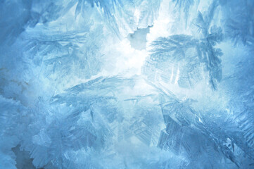 Abstract blue frozen pattern texture, frosted snowflakes close up background on the winter window