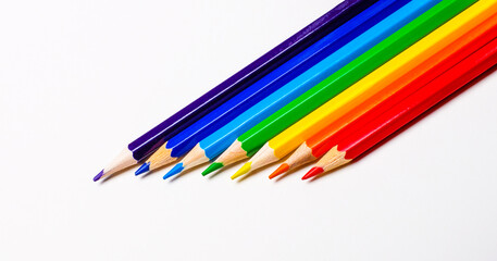 Fototapeta premium On a white background, color pencils from the side close-up stacked in the colors of the rainbow