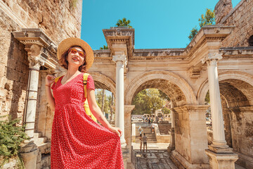 Fototapeta premium Happy female tourist traveler discover interesting places and popular attractions in the old city of Antalya, Turkey. The famous Roman gate of Hadrian in the background
