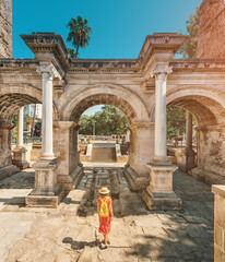 Fototapeta premium Happy female tourist traveler discover interesting places and popular attractions and walks in the old city of Antalya, Turkey. The famous Roman gate of Hadrian