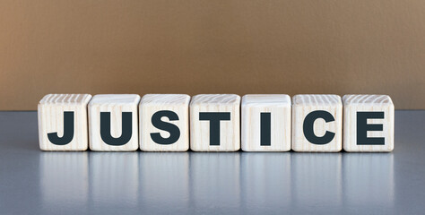 JUSTICE - word on wooden cubes on a beautiful gray background