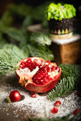 New year's atmosphere red pomegranate and green cake on the background of Christmas tree branches smelling of fir