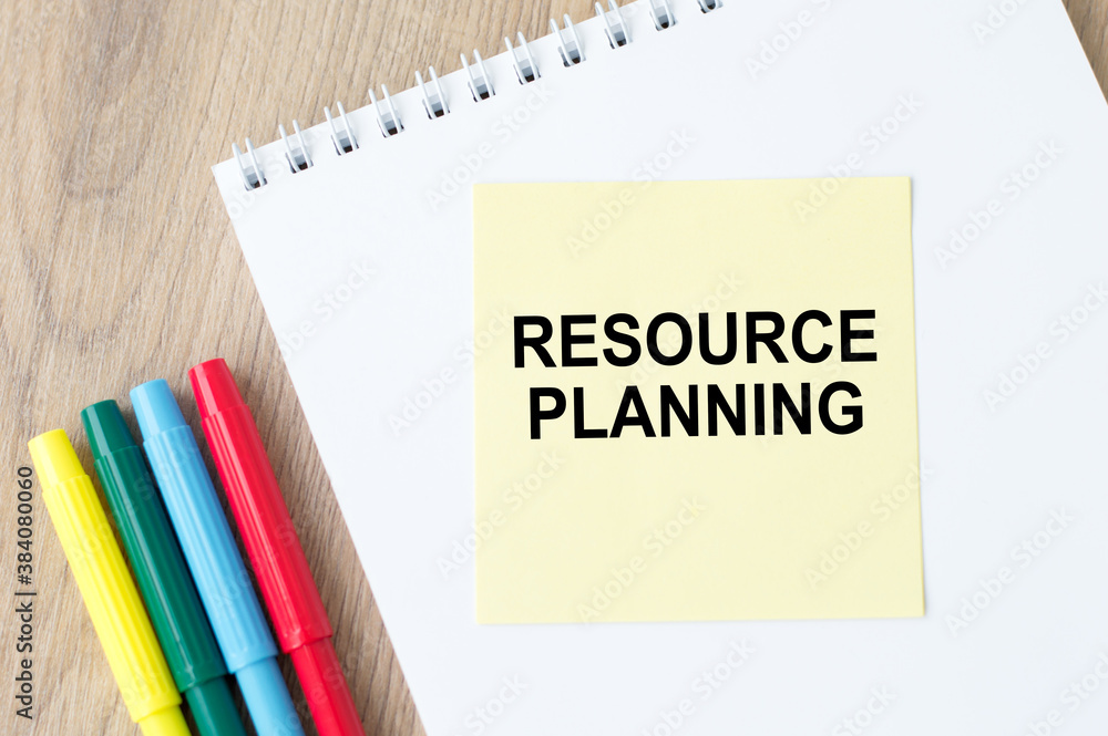 Poster resource planning text on the yellow sheet that flies on a notepad on the table, next to colorful ma